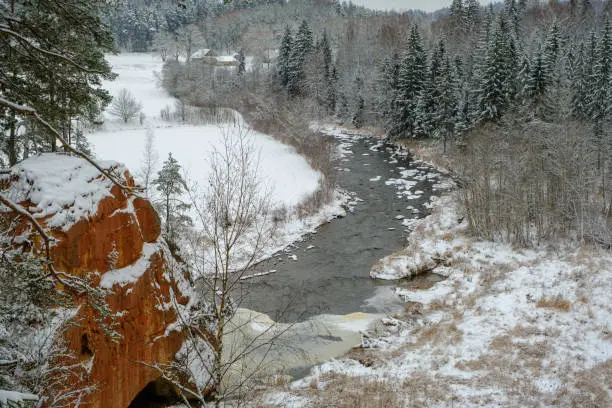 Photo of Sandstone rock. Zvartes rocks on the banks of the Amata River, on a white, snowy and cold winter day, Gauja National Park, Latvia