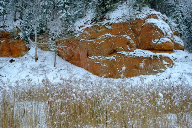 Photo of Sandstone rock. Zvartes rocks on the banks of the Amata River, on a white, snowy and cold winter day, Gauja National Park, Latvia