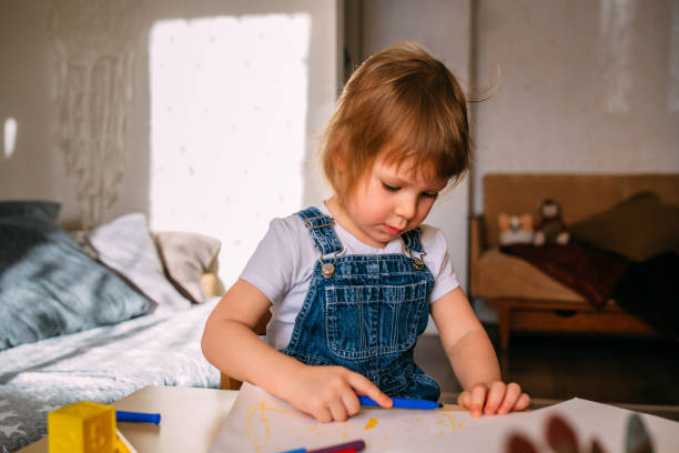 istock Small child at home at the children's table draws with felt-tip pens. 1445404239