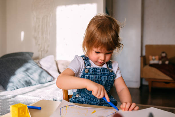 istock Small child at home at the children's table draws with felt-tip pens. 1445404243