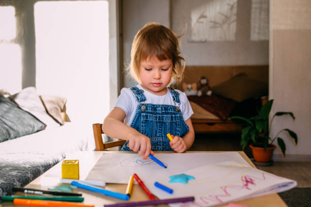 istock Small child at home at the children's table draws with felt-tip pens. 1445404258