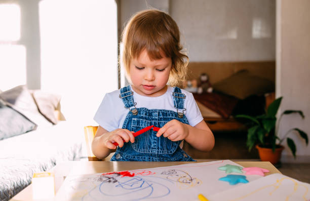 istock Small child at home at the children's table draws with felt-tip pens. 1445404279