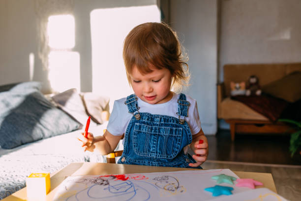 istock Small child at home at the children's table draws with felt-tip pens. 1445404280