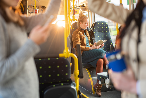 Happy woman reading a book while traveling by bus