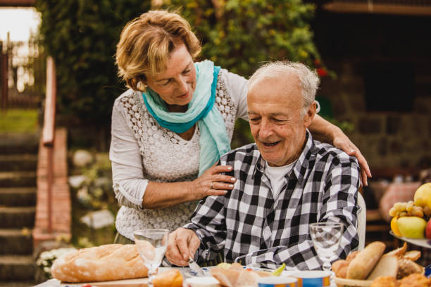 istock Caring senior woman embracing her loving husbnad from behind while having supper in their back yard 1445405833