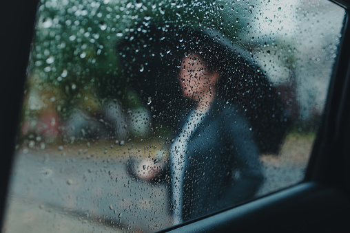 Empresaria con paraguas esperando bajo la lluvia fuera del coche photo