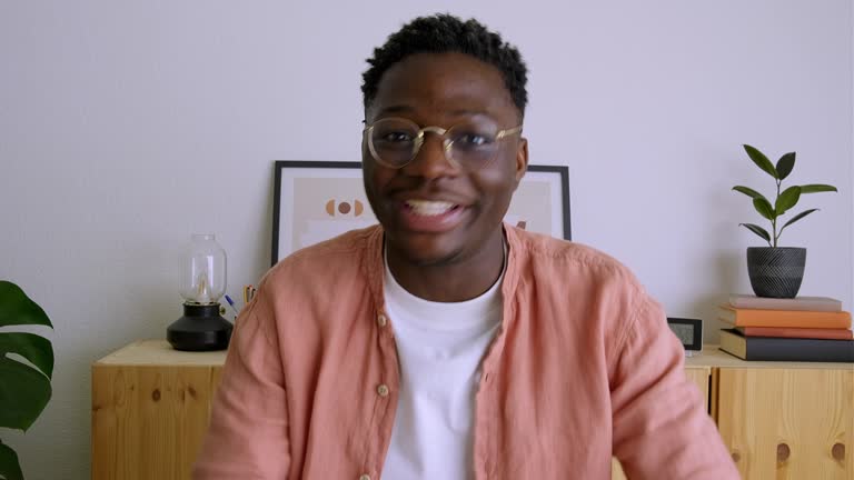 Screen view of yong Black man waving hand and talking during a video call looking at camera. 4k video.