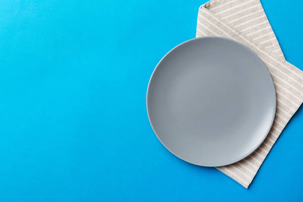 istock Top view on colored background empty round gray plate on tablecloth for food. Empty dish on napkin with space for your design 1445408291