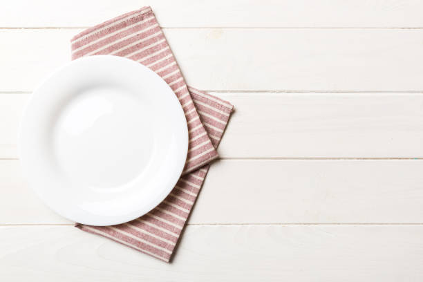 istock Top view on colored background empty round white plate on tablecloth for food. Empty dish on napkin with space for your design 1445408294