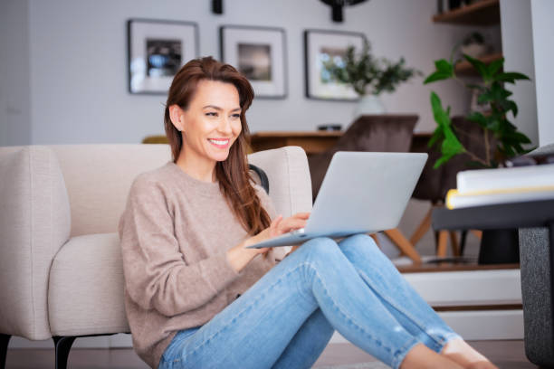 istock Smiling caucasian woman using laptop at home while sitting on the floor 1445412132