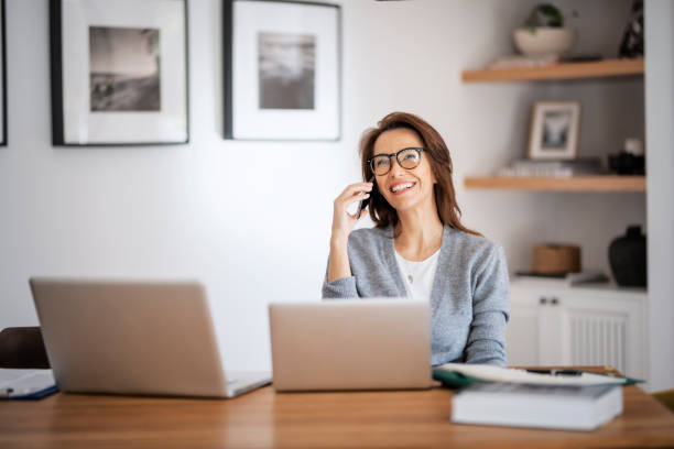 istock Business woman using mobile phone and laptops at home 1445412170