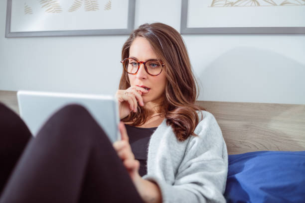 istock Worried woman using digital tablet in bed 1445414397