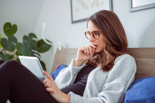 istock Worried woman using digital tablet in bed 1445414513