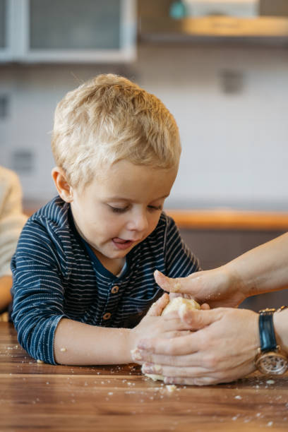 istock Young boy leaning on the kitchen counter and kneading cookie dough 1445416467