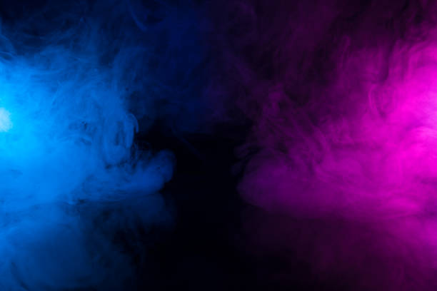 黒いテーブルの背景に青と紫のネオンライトのカラフルな煙の雲が渦巻く - air flow ストックフォトと画像