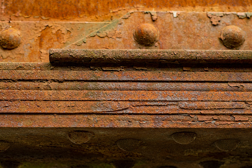 Old steel beams covered with rust. Strong fastening elements of the bridge made of iron plates fastened with rivets.