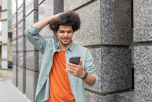 Man with afro hairstyle holding smart phone and touching his hair