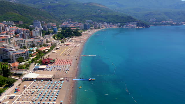 Aerial slowmotion video. View on a Becici beach in the city of Budva. Summer season in Montenegro