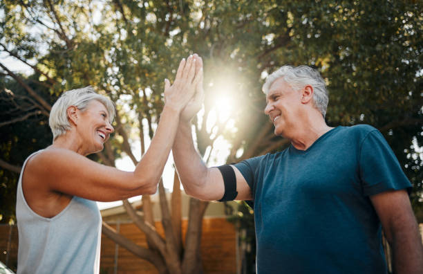 istock Fitness senior couple high five for support, teamwork and exercise motivation with sunshine, outdoor exercise and wellness. Success, achievement or target goal of elderly people for workout results 1445422967