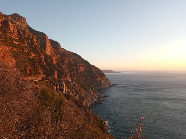 Landscape image of Chapman's peak drive during sunset Sunset above the oceans with red reflection on  the mountains chapmans peak drive stock pictures, royalty-free photos & images