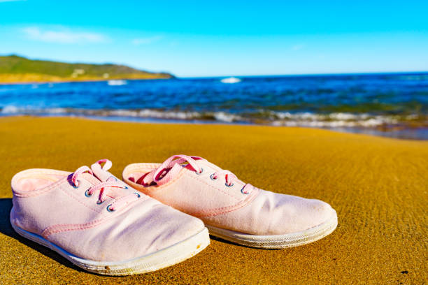 istock Female sneakers on sand beach 1445425633