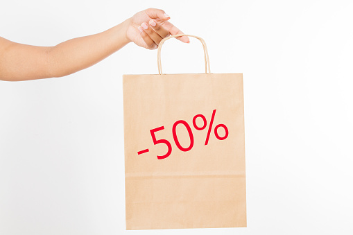 Sale - 50 % concept. Template blank package. African american woman hand holding a paper kraft bag isolated on white background. Delivery and shopping.