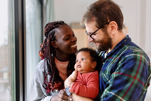 Happy parents spend time with their baby at home