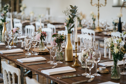 Elegant wedding banquet with golden vases, candlestick holders and little flower bouquets