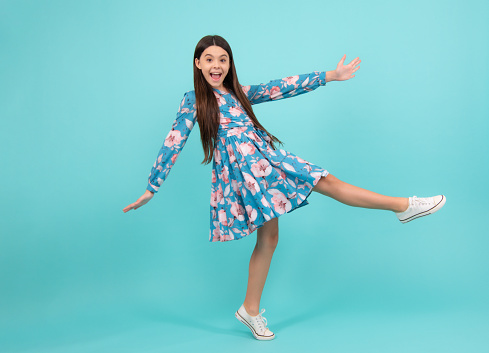 Happiness, freedom, motion and child. Young teenager girl jumping over blue background, funny jump. Excited teenager, amazed and cheerful emotions