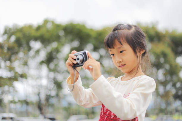 istock a Asian girl take photos with a digital camera. 1445439305