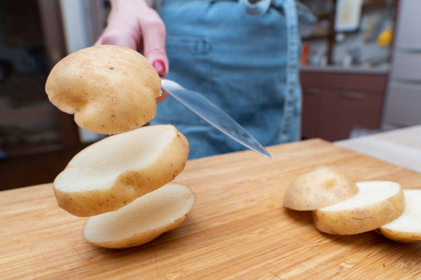 raw potato slices on wooden cutting board close-up