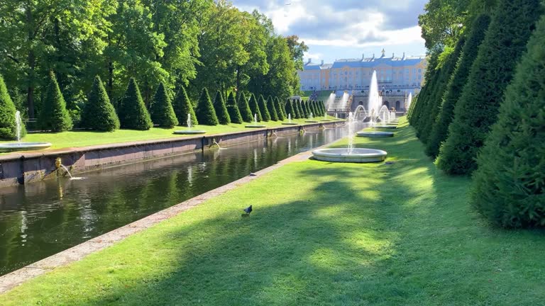 Petergof. Grand Palace, fountains with canal and many tourists in the lower park of Peterhof on a bright sunny day