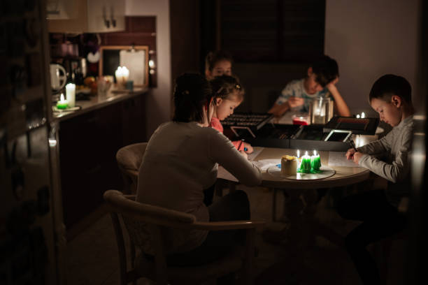la famille passe du temps ensemble pendant une crise énergétique en europe provoquant des pannes de courant. les enfants dessinent dans l’obscurité. - crisis house burning color image photos et images de collection