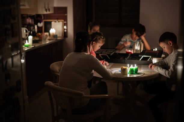 Family spending time together during an energy crisis in Europe causing blackouts. Kids drawing in blackout. Family spending time together during an energy crisis in Europe causing blackouts. Kids drawing in blackout. blackout stock pictures, royalty-free photos & images