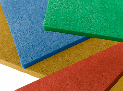 square pieces of green, red, blue and brown sponge foam stacked. colorful thin material isolated on a white background