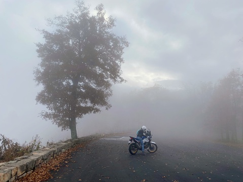 Scenic view of lone biker driving through clouds in Blue Ridge Mountains. The photo was taken 10/26/2022 on skyline drive, Virginia.