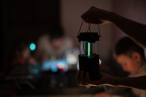 Family spending time together during an energy crisis in Europe causing blackouts. Led lantern in hands.