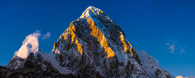 Golden sunset light illuminating the snow capped peak of Pumori 7161m high in the Himalayan mountains of Nepal.