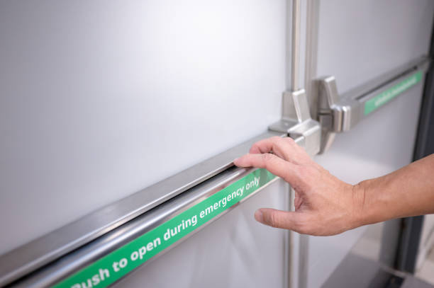 Male hand pushing panic bar on emergency fire exit door Male hand pushing stainless steel panic bar opening the emergency fire exit door in public building. Fire escape concept door panel stock pictures, royalty-free photos & images