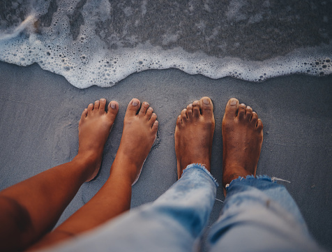 Couple feet, beach sand and water at ocean waves, nature and summer travel for vacation, honeymoon date and tropical holiday outdoors. Closeup above man, woman and foot toes at sea, relax and freedom