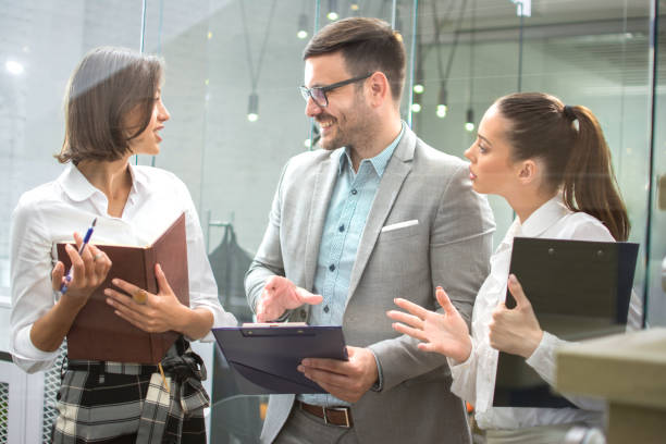 istock Group of young business people discussing documents together in office lobby. 1445456036