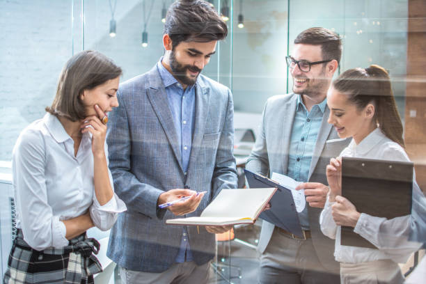 istock Young business people discussing over business report while standing in office hallway. 1445456231