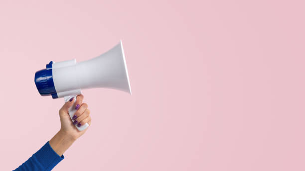 istock Woman hand with megaphone on pink background. Creative announcement concept. 1445457129