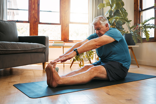 Health, exercise and yoga with senior man doing ground stretching before meditation and wellness workout. Fitness, relax and floor warm up by elderly male start healthy cardio training in living room
