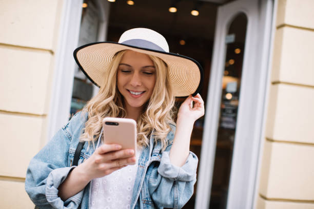 istock Smiling woman in hat thoughtfully browsing smartphone 1445460847