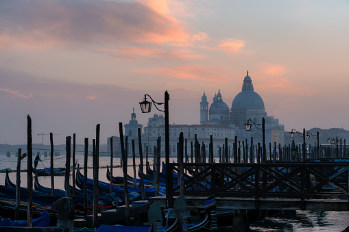 Looking out across a line of gondolas on the magnificent Grand Canal in Venice at sunset, with the majestically-domed Santa Maria della Salute Basilica in the background.