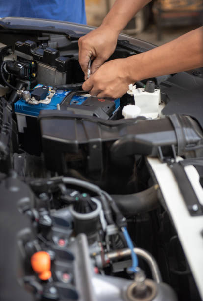 istock Car service by an auto mechanic in garage, fixing a car battery. 1445463205