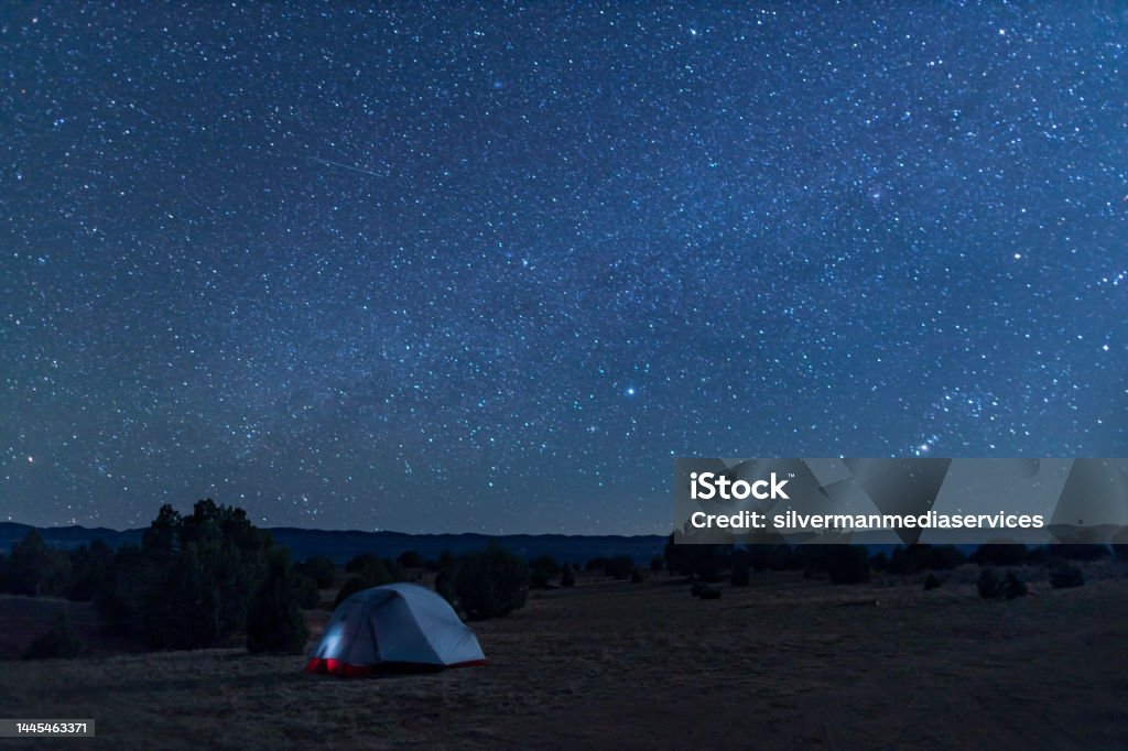 Tent Under Starry Night Sky - Grand Staircase-Escalante National Monument, Utah A tent under a star-filled night sky in the Grand Staircase-Escalante National Monument, a few miles south of the town of Escalante, Utah. Fiftymile Mountain is seen in the distance. Adventure Stock Photo