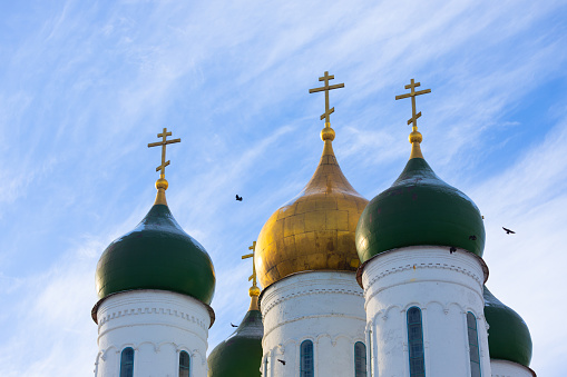 Green and golden domes of the Orthodox Church with golden crosses against the blue sky