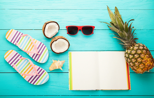 Summer plan and accessories, fruits and notebook on blue wooden background. Copy space